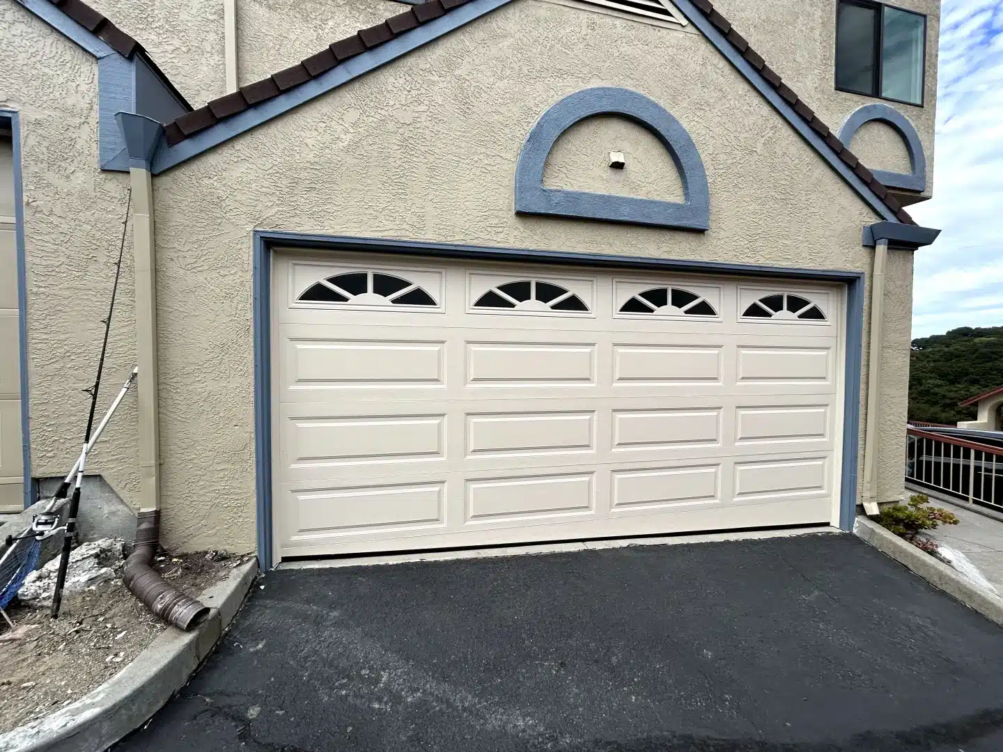 A beige traditional panel door with arched sunray windows complements a stucco exterior, demonstrating quality service from a trusted garage door repair company in Alameda, CA.